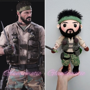 Op de afbeelding: De afbeelding toont een vergelijking van een man in militaire kleding en een gehaakte pop. De man draagt een beige overhemd, een camouflagebroek en een tactisch vest. De pop is een gehaakte versie van de man, met vergelijkbare kleding en accessoires.