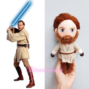 Op de afbeelding: Een gehaakt pluche speelgoedje van een Jedi-ridder met een bruine baard en blauwe ogen. Het speelgoed draagt een beige gewaad en bruine laarzen.
