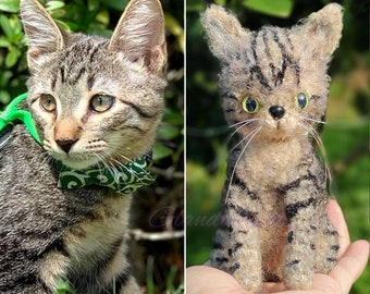 May include: Two tabby cats, one a real cat wearing a green and white patterned collar and the other a needle felted cat, both looking at the camera.