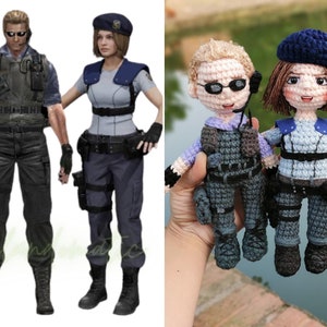 Könnte beinhalten: Zwei gehäkelte Figuren eines Mannes und einer Frau, die taktische Ausrüstung tragen. Der Mann trägt eine schwarze Weste und eine Sonnenbrille. Die Frau trägt eine blaue Weste und eine blaue Baskenmütze.