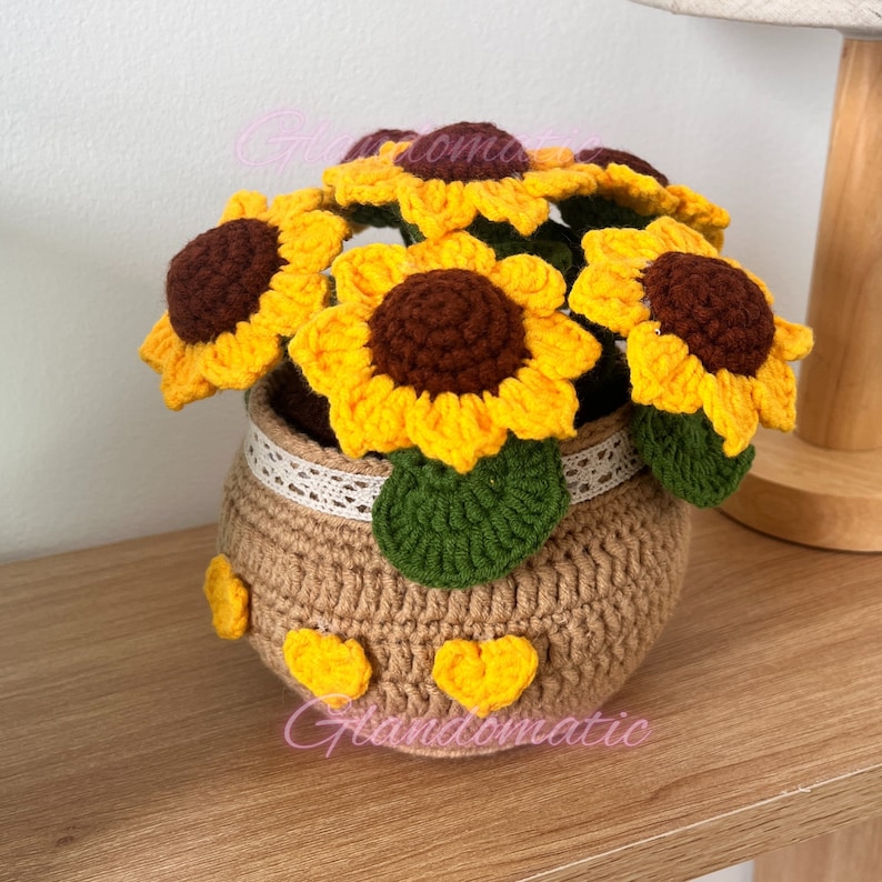 Peut inclure: Un bouquet de tournesols en crochet dans un pot brun avec une bordure en dentelle blanche. Le pot est d&eacute;cor&eacute; d'embellissements en forme de c&oelig;ur jaunes.