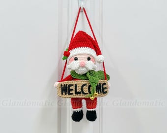 Può includere: Decorazione per porta a uncinetto a forma di Babbo Natale, con cappello e abito rossi e stivali neri. La figura di Babbo Natale tiene in mano un cartello con la scritta "WELCOME" in nero. Una sciarpa verde e una piccola campana aggiungono dettagli festosi.