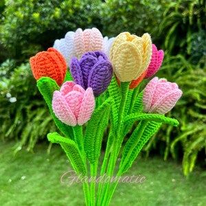 May include: A bouquet of handmade crochet tulips in various colors, including orange, white, pink, purple, and yellow. The flowers have green stems and leaves. The image includes the text "Glandomatic".