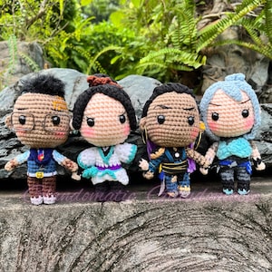 K&ouml;nnte beinhalten: Vier geh&auml;kelte Pl&uuml;schfiguren, jede mit einzigartigen Gesichtsausdr&uuml;cken und Kleidung. Die Figuren stehen auf einer strukturierten Oberfl&auml;che. Die Figuren tragen eine Brille, ein wei&szlig;-blaues Kimono, ein lila-schwarzes Outfit und ein blau-wei&szlig;es Outfit.