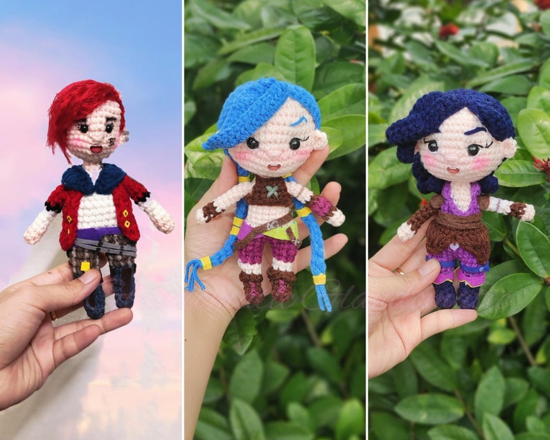 May include: Three crocheted figures, each with a different hairstyle and outfit. The figure on the left has red hair and a red jacket, the middle figure has blue hair and a purple top, and the figure on the right has blue hair and a purple top.