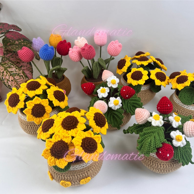 Peut inclure: Une collection d'arrangements floraux en crochet dans des pots. Les arrangements comprennent des tournesols, des tulipes et des fraises. Les pots sont en toile de jute et ont un aspect rustique.