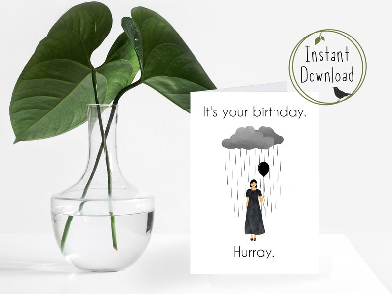 May include: A birthday card with a black and white illustration of a person holding a black balloon under a gray rain cloud. The text on the card reads "It's your birthday. Hurray."