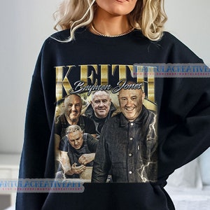 May include: Black sweatshirt with a gold graphic print of the band "Keith Brymer Jones". The graphic features a photo of the band members and the band's name in gold lettering.
