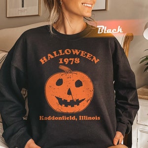 Könnte beinhalten: Schwarzes Sweatshirt mit einem Vintage-Halloween-Motiv mit einem Kürbis und dem Text "Halloween 1978 Haddonfield, Illinois".