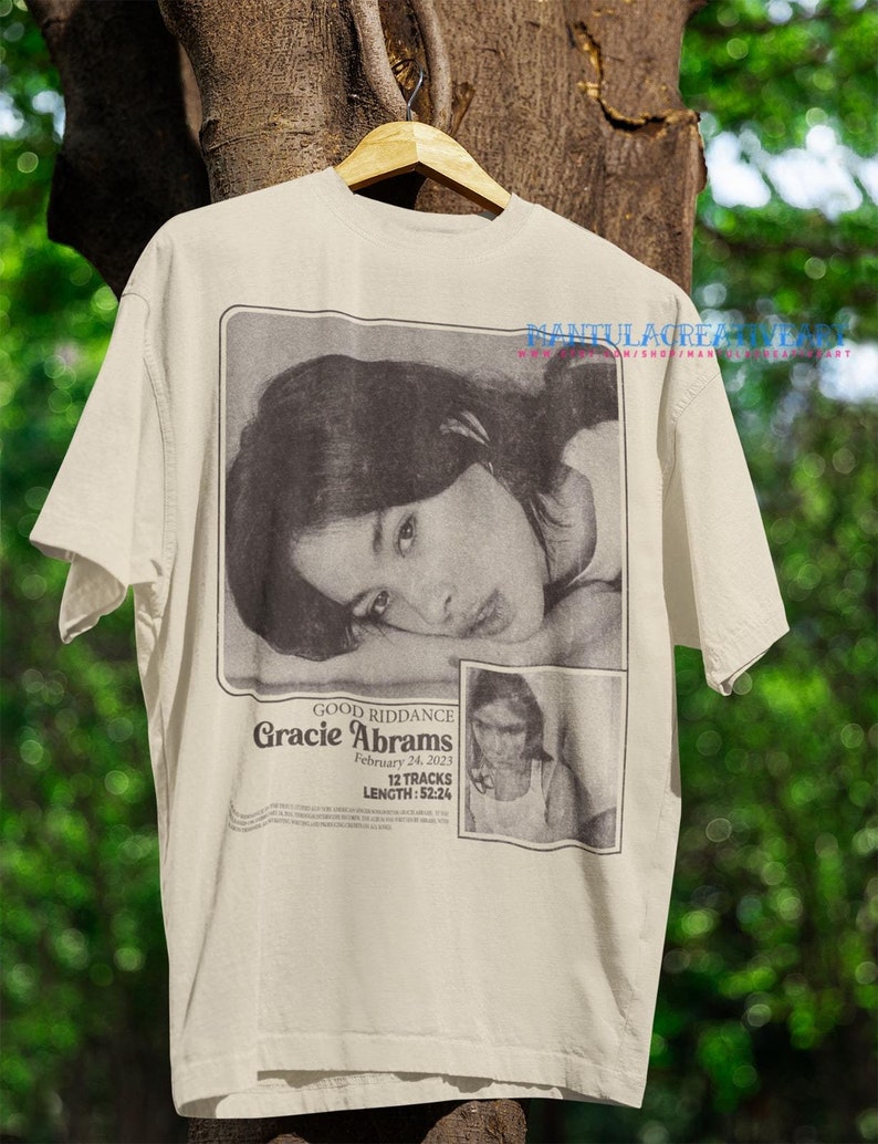 May include: A beige t-shirt with a black and white image of a woman and text that reads "GOOD RIDDANCE Gracie Abrams February 24, 2023 12 TRACKS LENGTH: 52:24"
