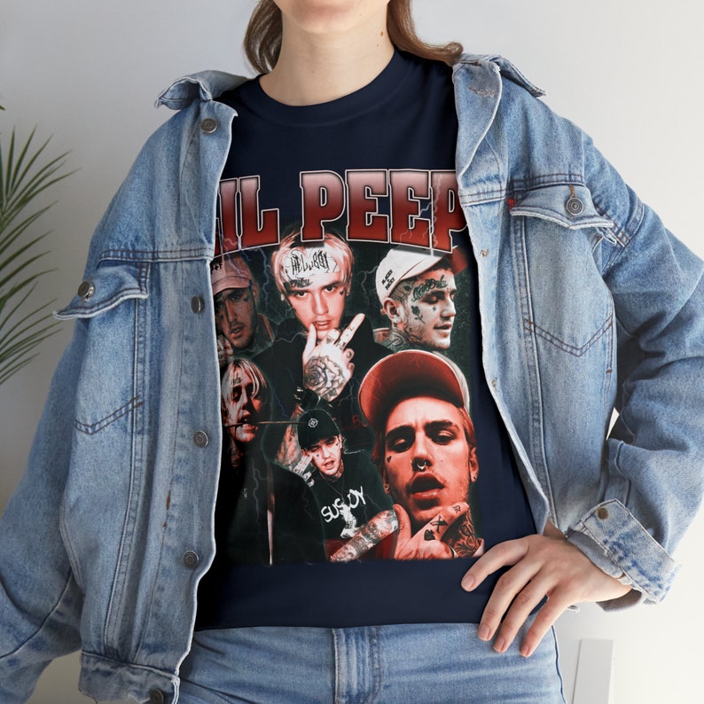 Pu&ograve; includere: Una t-shirt blu navy con un collage di immagini di Lil Peep e il testo "Lil Peep" in lettere rosse.