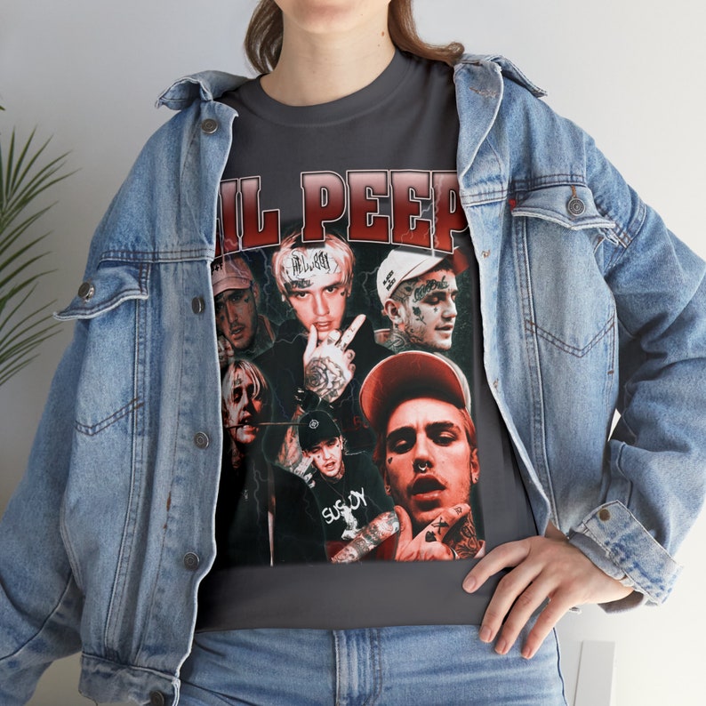 Pu&ograve; includere: Una maglietta grigia scura con una grafica in stile vintage di Lil Peep e altri musicisti. La grafica &egrave; in rosso, bianco e nero, e presenta il testo "Lil Peep".