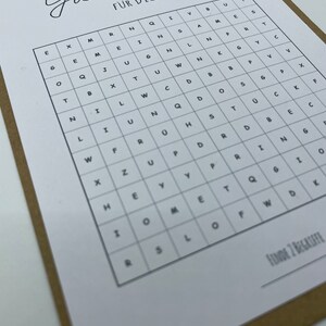 May include: A black and white word search puzzle with the title "Gutschein f&uuml;r Dich" (Gift Certificate for You). The puzzle is on a brown background.