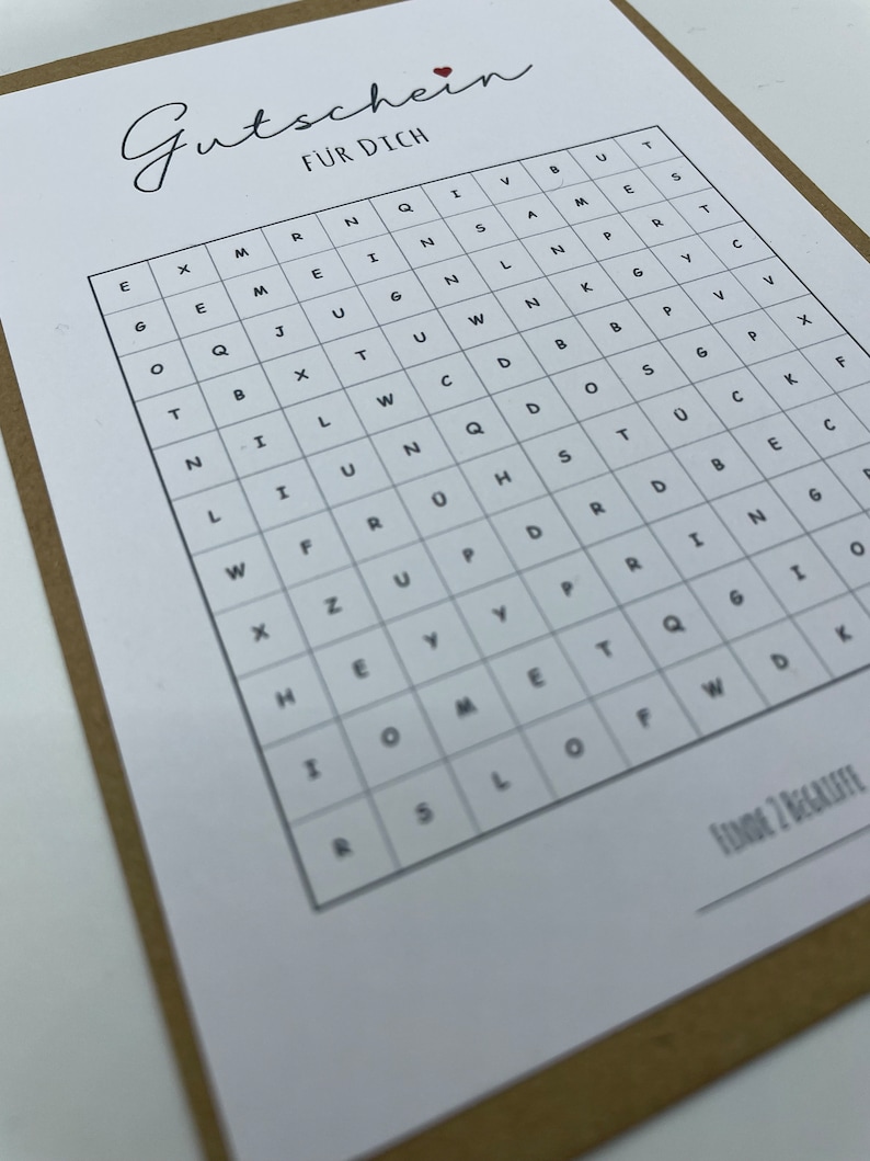 May include: A black and white word search puzzle with the title "Gutschein f&uuml;r Dich" (Gift Certificate for You). The puzzle is on a brown background.