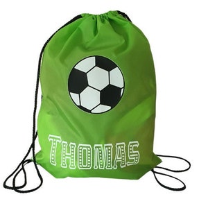 May include: Green drawstring bag with a black and white soccer ball graphic and the name "THOMAS" printed in white.
