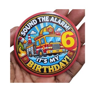 May include: Red and yellow round button with a cartoon fire truck, a fireman, and the text "Sound the Alarm! It's My Birthday!" with the number 6 in a yellow circle.