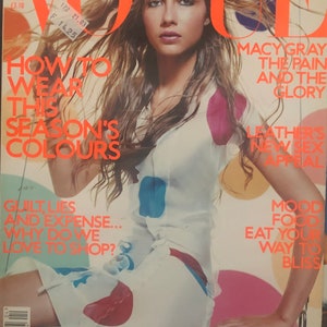 Op de afbeelding: Een Vogue-tijdschriftomslag van april met een persoon met lang golvend haar in een witte jurk met grote rode, blauwe en gele stippen. De tekst op de omslag bevat koppen zoals How to Wear This Season's Colours en Macy Gray The Pain and the Glory.