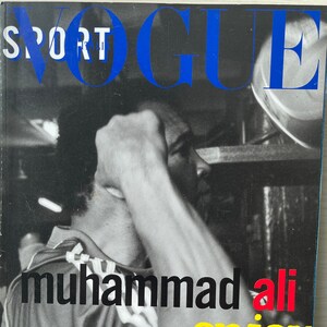 Puede incluir: Una foto en blanco y negro de Muhammad Ali en la portada de la revista Vogue. La portada de la revista es azul y blanca con la palabra "SPORT" en letras blancas y "VOGUE" en letras azules. El texto "enjoy the GAME" está en letras amarillas.