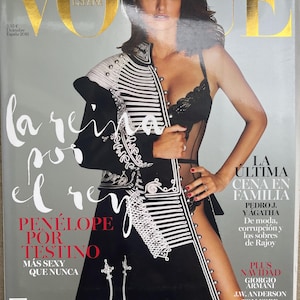 Op de afbeelding: Een uitgave van het tijdschrift Vogue España uit december 2016 met een cover waarop een persoon een zwart militair jasje met wit borduurwerk over een zwarte kanten bodysuit draagt. De cover bevat de tekst VOGUE, ESPAÑA en diverse koppen.