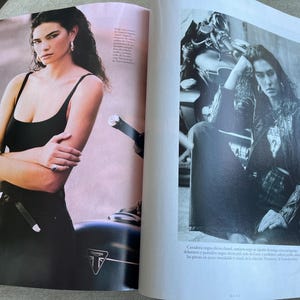 Puede incluir: Un conjunto de camiseta sin mangas negra y pantalones negros. La modelo lleva joyas de plata y est&aacute; de pie junto a una motocicleta. La motocicleta tiene un cuerpo negro y detalles plateados. El logotipo de Triumph es visible en la motocicleta.