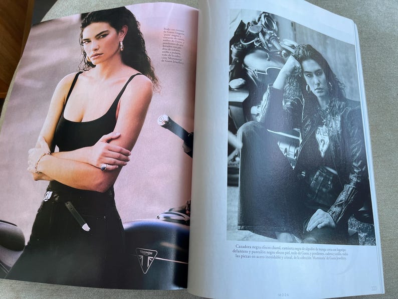 Puede incluir: Un conjunto de camiseta sin mangas negra y pantalones negros. La modelo lleva joyas de plata y est&aacute; de pie junto a una motocicleta. La motocicleta tiene un cuerpo negro y detalles plateados. El logotipo de Triumph es visible en la motocicleta.