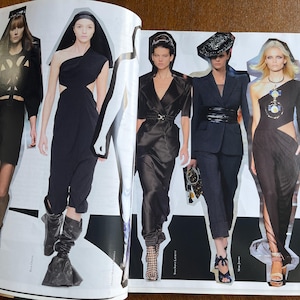 May include: A magazine spread showcasing five models in black attire. The outfits include a cut-out dress, a blazer with matching trousers, and a one-shoulder dress. The models are wearing accessories such as hats and jewellery.