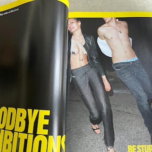 May include: A magazine spread featuring two models in Diesel clothing. The woman wears a black leather jacket and dark denim pants. The man wears jeans and has a white shirt draped over his shoulders. The text "GOODBYE INHIBITIONS" is visible.