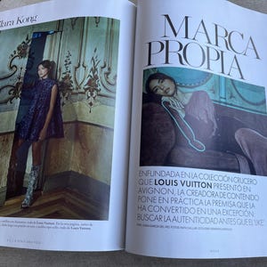 Puede incluir: Una revista de moda de doble p&aacute;gina. Una p&aacute;gina presenta a una modelo con un vestido azul oscuro y botas estampadas. La otra p&aacute;gina tiene el texto "MARCA PROPIA". Tambi&eacute;n se ve el nombre "Clara Kong".