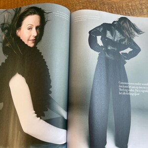 May include: A fashion magazine spread featuring a woman wearing a black, textured shawl over a white long-sleeved top. The other image shows a person in a black leather jacket, wide-leg pants, and a belt. The background is a light gray.