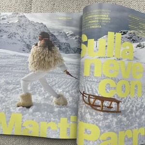 Puede incluir: Una p&aacute;gina de revista con una persona con ropa de esqu&iacute; blanca y un chal de piel, esquiando en un paisaje monta&ntilde;oso nevado. El texto "Sulla neve con Martin Parr" est&aacute; en letras amarillas grandes.