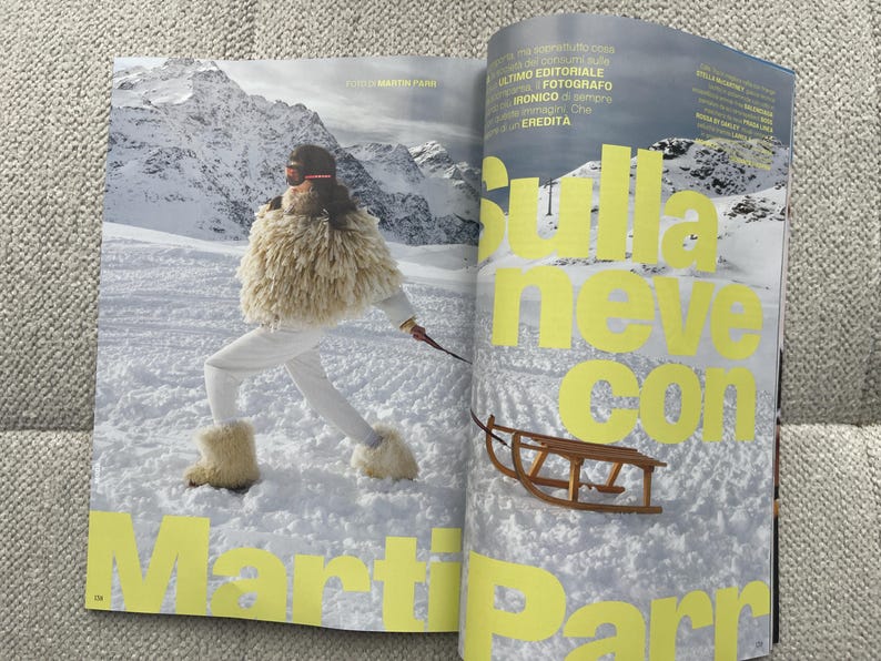 Puede incluir: Una p&aacute;gina de revista con una persona con ropa de esqu&iacute; blanca y un chal de piel, esquiando en un paisaje monta&ntilde;oso nevado. El texto "Sulla neve con Martin Parr" est&aacute; en letras amarillas grandes.
