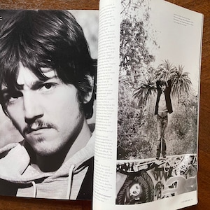 May include: A black and white photo of a man with short dark hair and a mustache. He is wearing a hooded sweatshirt. The photo is from a magazine and includes text that reads "Ever since I was a young kid I've liked to lies Th discovered a career that pays for that."