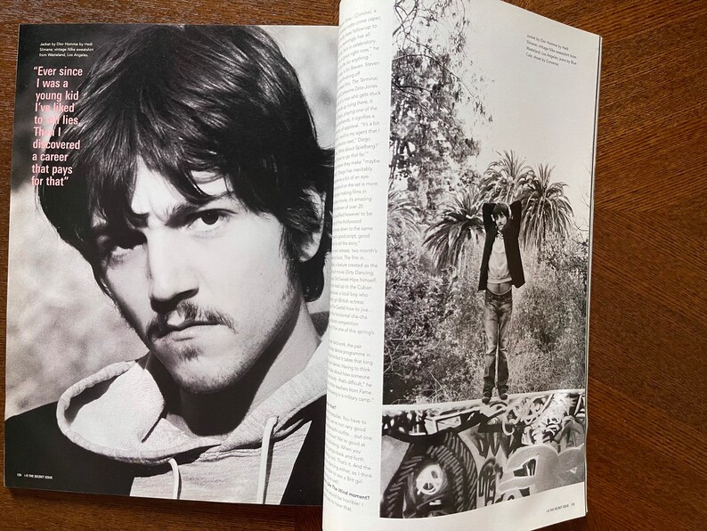 May include: A black and white photo of a man with short dark hair and a mustache. He is wearing a hooded sweatshirt. The photo is from a magazine and includes text that reads "Ever since I was a young kid I've liked to lies Th discovered a career that pays for that."