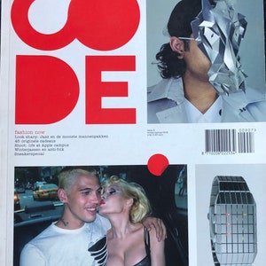 Puede incluir: Una portada de revista con la palabra "CODE" en letras rojas grandes. La portada presenta una foto de una pareja en un coche, una foto de una persona con una máscara plateada y una foto de un reloj digital plateado con luces rojas.