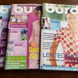 May include: A collection of fashion magazines with vibrant covers. The magazines showcase articles on bridal fashion, sewing, and spring trends. The covers feature models and text in multiple languages, including Dutch and German.