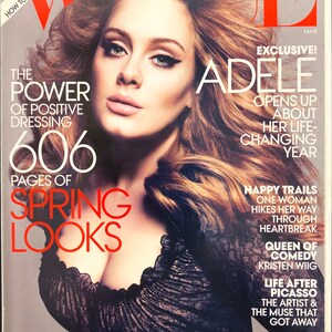 Op de afbeelding: Een maart-editie van het tijdschrift Vogue met een coverfoto van Adele met volumineus bruin haar. De cover bevat teksten zoals The Power of Positive Dressing, 606 Pages of Spring Looks en Exclusive! Adele Opens Up About Her Life-Changing Year.