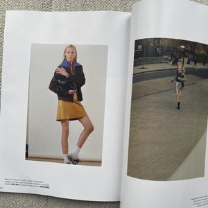 Puede incluir: Una p&aacute;gina de revista de moda con una mujer con una falda color mostaza, una chaqueta marr&oacute;n con cuello azul y un bolso negro. La revista tambi&eacute;n muestra a una persona corriendo por una calle.