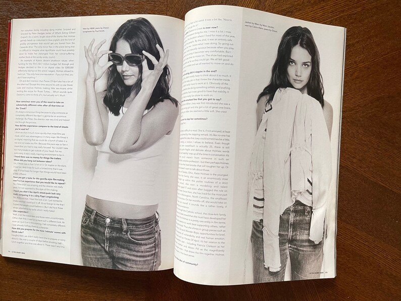 May include: A black and white photo of a woman wearing a white t-shirt and blue jeans. She is looking at the camera and holding her sunglasses in her hands. The photo is from a magazine and includes text about the woman.
