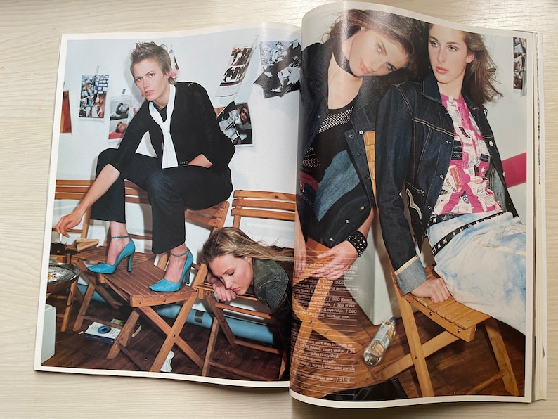 May include: Two women are sitting on wooden chairs. One woman is wearing a black jacket and blue jeans, and the other woman is wearing a denim jacket and jeans. Both women are wearing blue shoes.