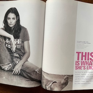 May include: A black and white photo of a woman sitting on the ground wearing blue jeans and a t-shirt with the text "M*A*S*H 40*TH" printed on it. The text "This is what she's like" is printed in pink on the right side of the image.