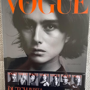 May include: A Vogue NL magazine cover featuring a black and white portrait of a person with short hair. The word "VOGUE" is in large orange letters at the top. The text "The Dutch" is at the bottom, along with other text.