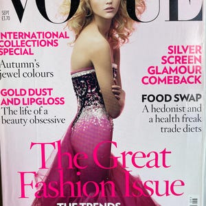 Può includere: Un numero di settembre della rivista Vogue con una persona dai capelli biondi che indossa un abito magenta senza spalline, aderente, con decorazioni di paillettes nere e argento sul corpetto. Il testo di copertina include The Great Fashion Issue.