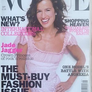Op de afbeelding: Een Vogue tijdschriftomslag met Jade Jagger in een lichtroze kanten jurk met ruches aan de mouwen. De tekst op de omslag bevat koppen zoals What's New, International Collections, Shopping Heaven en The Must-Buy Fashion Issue.