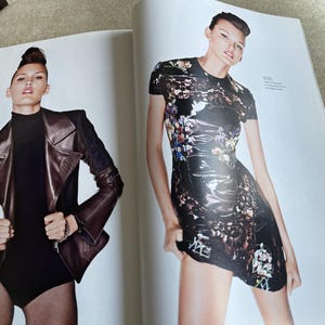 May include: Two-page spread from a fashion magazine featuring a model in two different outfits. On the left, a brown leather jacket with black accents and a black bodysuit. On the right, a black dress with a floral pattern.
