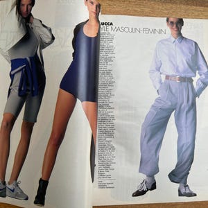 May include: A fashion magazine spread featuring three models. One model wears a white jacket, gray shorts, and a blue wrap. Another model is in a navy blue bodysuit. The third model is in a white shirt and light blue pants.