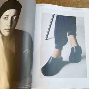 May include: Black and white magazine spread featuring a portrait of a person wearing a black beanie and top. The text "Geertje Sur" is visible. The opposite page shows a person wearing dark blue pants and black shoes.