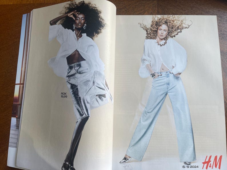May include: A fashion magazine spread featuring two models. One model is in a white blouse and silver skirt, the other in a white blouse and light blue trousers. The H&M logo and S/S 2024 text are visible.