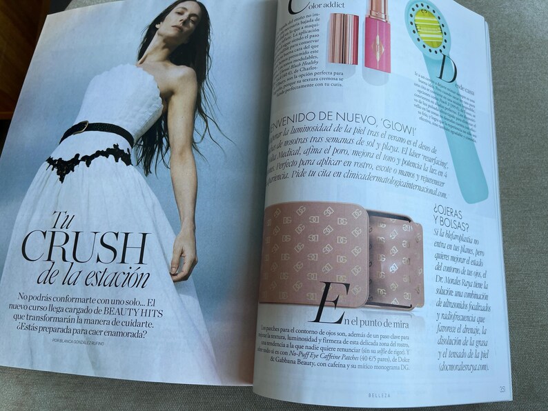 Puede incluir: Una p&aacute;gina de revista de moda con una mujer con un vestido blanco de un solo hombro con cintur&oacute;n negro y detalles de encaje. El texto "Tu CRUSH de la estaci&oacute;n" es visible, junto con otros textos y productos de belleza.