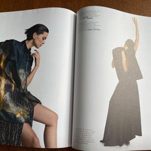 Puede incluir: Una p&aacute;gina doble de revista de moda con dos modelos. Una modelo est&aacute; sentada, con una chaqueta oscura estampada sobre una falda de lentejuelas. La otra modelo est&aacute; de pie, con un vestido largo y oscuro con una capa.