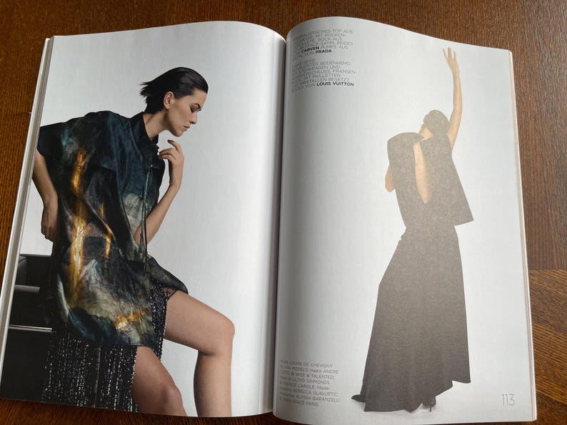 Puede incluir: Una p&aacute;gina doble de revista de moda con dos modelos. Una modelo est&aacute; sentada, con una chaqueta oscura estampada sobre una falda de lentejuelas. La otra modelo est&aacute; de pie, con un vestido largo y oscuro con una capa.